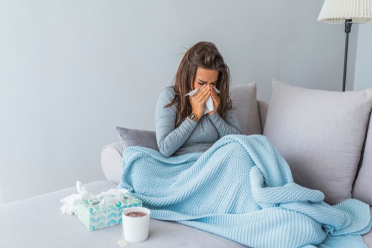 Mujer joven en el sofá enferma con gripe y refriado.