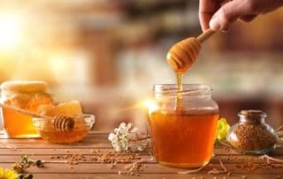 Miel en tarro de cristal con flores sobre mesa de madera.