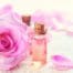 Aceite esencial de rosa de damasco en botellita de cristal junto a flor de rosa de damasco.