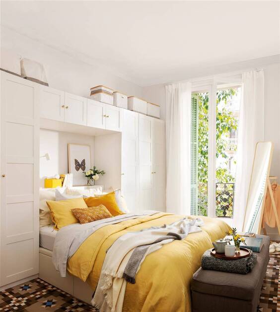 Decoracion de habitación pequeña con elementos decorativos: cojines cuadros, espejo, estantes y cajas 