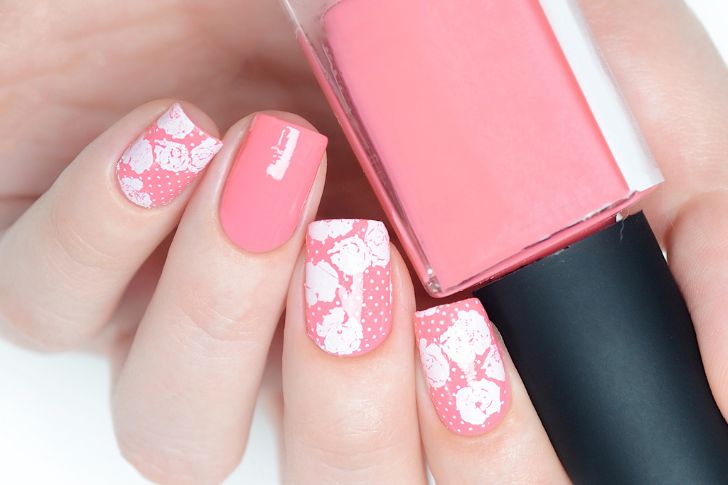 Uñas en color rosa claro decoradas con flores y lunares blancos.