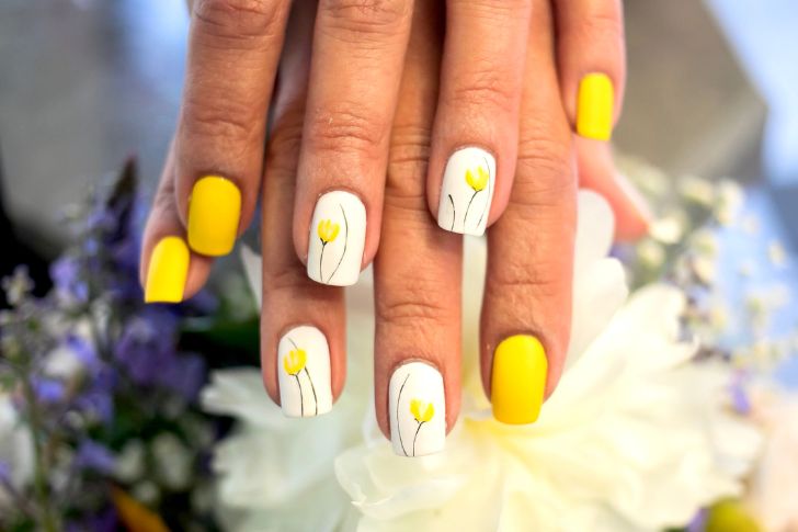 Manicura floral con uñas amarillas y blancas con flores amarillas